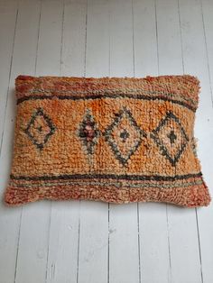 an orange and black rug laying on top of a wooden floor next to a white wall