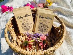 two baby bloom seed packets sitting in a wicker basket on a blanket with flowers