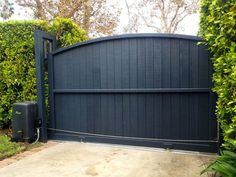 a black gate is open in front of some bushes