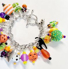 Show your Halloween spirit wearing this one-of-a-kind charm bracelet. Silver wrapped lamp work glass beads, ceramic beads, agate stones, resin beads, seed beads, and metal charms in shades of orange, red, green, yellow, black, and purple. Charms are hung individually on a stainless-steel chain and finished with the clasp of your choice.  This bright and colorful beaded charm bracelet comes with a variety of the charms shown with one on every chain link on the bracelet from end to end.  The bracelet length shown in the picture measures 7 inches and can be adjusted as requested prior to checkout. Please measure your wrist to insure a proper fit, prior to purchase.  All beads are wire wrapped by me with great attention to detail. Bead size, shape, and color composition may vary from picture s Handmade Charm Bracelet For Halloween Gift, Handmade Halloween Charm Bracelet Gift, Purple Charms, Chunky Charm Bracelet, Charm Bracelet Silver, Beaded Charm Bracelet, Color Composition, Hippie Bracelets, Halloween Charms