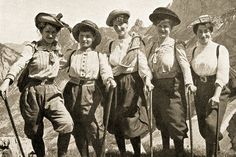 an old black and white photo of five people with skis standing in the mountains