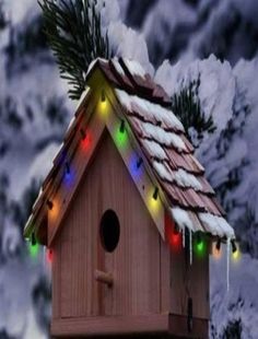 a birdhouse with lights on it in the snow