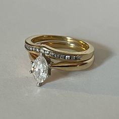 two gold wedding rings with diamonds on each one and an oval shaped diamond in the middle