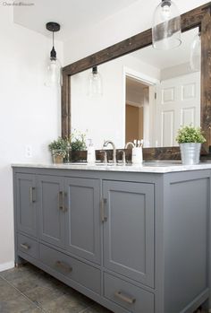 a bathroom with a large mirror and gray cabinets