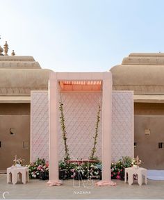 an outdoor ceremony setup with flowers on the altar and two small stools in front of it