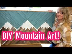 a woman standing next to a painting with the words diy mountain art