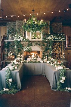 a table with flowers and candles is set up in front of a stone fire place