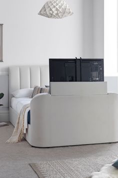 a living room with a white couch and television set on top of the tv stand