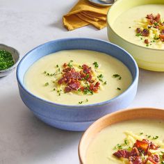 three bowls filled with soup and garnished with bacon, parsley and chives