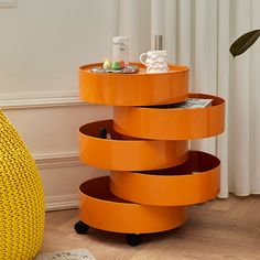 an orange round table with drawers on it in a room next to a yellow chair