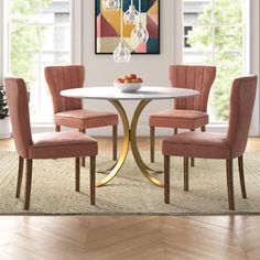 a dining room table with four chairs and a painting on the wall in the background