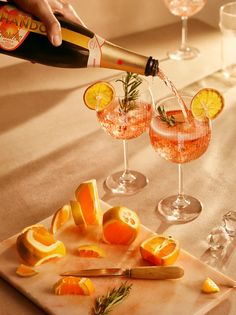 someone is pouring wine into two glasses with oranges