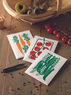 three vegetable stickers sitting on top of a wooden table next to tomatoes and carrots