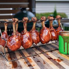 several pieces of meat are being cooked on a grill with tongs and a green cup