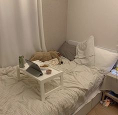 an unmade bed with a laptop on it and a teddy bear in the corner