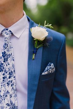 a man in a blue suit with a white rose on his lapel