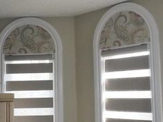 two arched windows with roman shades in a bathroom