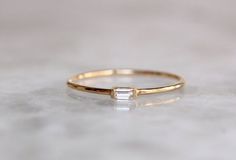 a gold ring with a baguette cut diamond on the side, sitting on a table