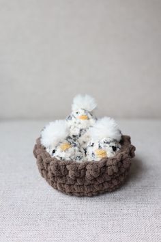 a small crocheted basket with white and brown stuff in it on a table