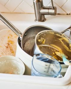 dirty dishes are sitting in the sink with utensils and measuring tape on them