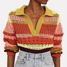 a woman wearing an orange, yellow and pink sweater with crocheted details on the shoulders