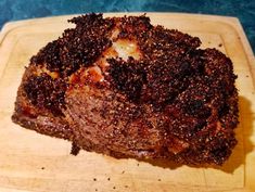 a piece of meat is sitting on a cutting board with some brown stuff around it