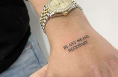 a person with a wrist tattoo that says by any means necessary on the wrist,