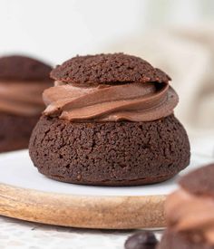 two chocolate cookies with frosting on a white plate