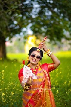 a woman in an orange and yellow sari holding a white object up to her head