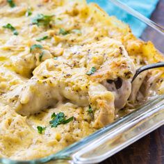 a casserole dish with chicken, cheese and parsley in it on a wooden table