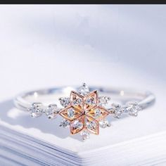 a white and pink diamond ring sitting on top of a book