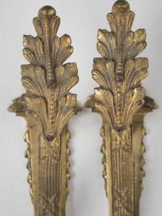 two ornate gold colored wall sconces on a white background