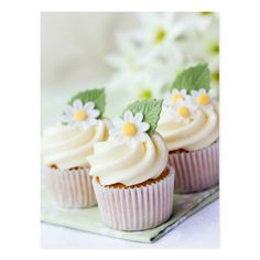 three cupcakes with white frosting and green leaves on them sitting on a plate