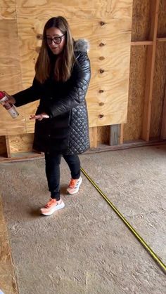 a woman standing in front of a wooden wall