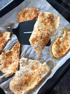 four pieces of chicken sitting on top of a sheet of tin foil next to a spatula