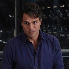 a man in a blue shirt is looking at the camera with an intense look on his face