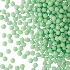 green beads are scattered in the air on a white background