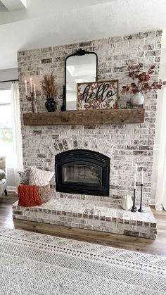 a living room with a brick fireplace and white rugs on the hardwood flooring