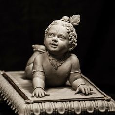 a small statue of a baby sitting on top of a book with an earring in it's hair