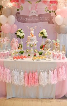 a table topped with lots of food and balloons in front of a bunny themed wall