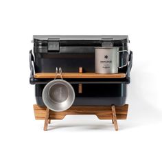 a black cooler with two pans and a wooden tray on the side, sitting next to each other