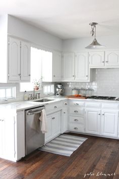 a kitchen with white cabinets and wood floors