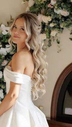 a woman in a white dress standing next to flowers