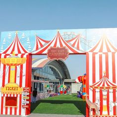 the entrance to an amusement park is decorated with red and white striped tents