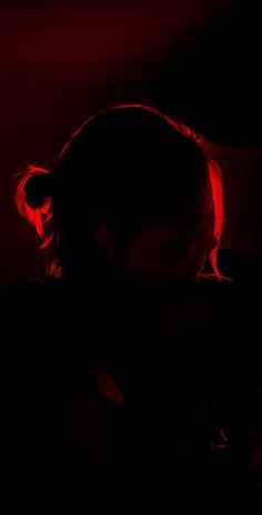 a woman is sitting in the dark with red light