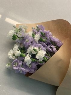 purple and white flowers are wrapped in brown paper