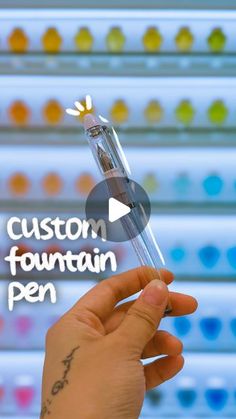 a person holding up a glass tube with the words custom fountain pen on it