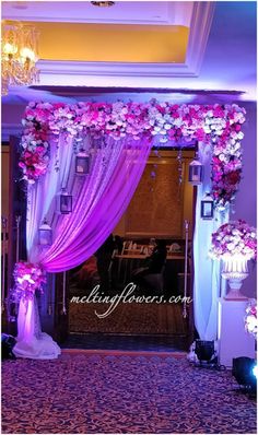 an entrance decorated with flowers and purple draping for a wedding or reception ceremony