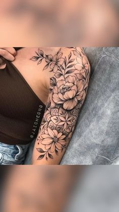 a woman's arm with flowers on it and a tattoo design on the arm