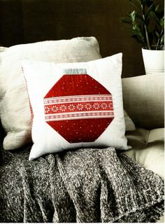 a red pillow sitting on top of a couch next to a potted green plant